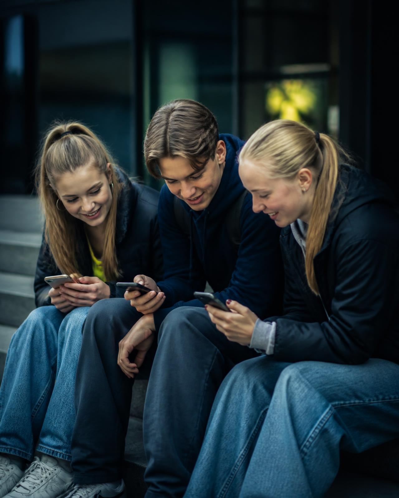 Personer som sitter på en trappa och surfar tillsammans på sina mobiler